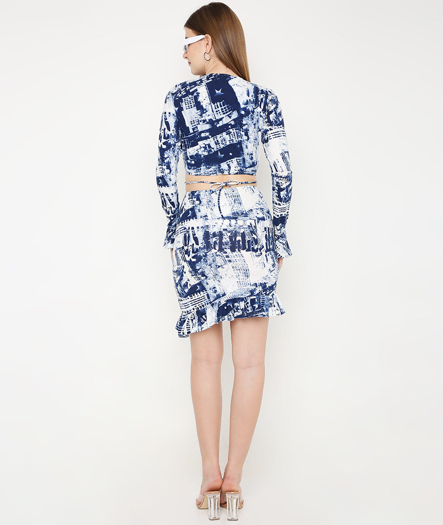 Full-length blue tie-dye co-ord set. Model wearing wrap top and mini skirt. Matching print resort outfit. Designer two-piece look. Chic vacation fashion. Modern minimalist matching set. Versatile fashion co-ord. Polished wardrobe staple. Sleek silhouette separation. Casual luxury wear. High-end lifestyle fashion. Premium women apparel. Detailed tie-dye pattern. Fitted blue print set. Contemporary resort style.
