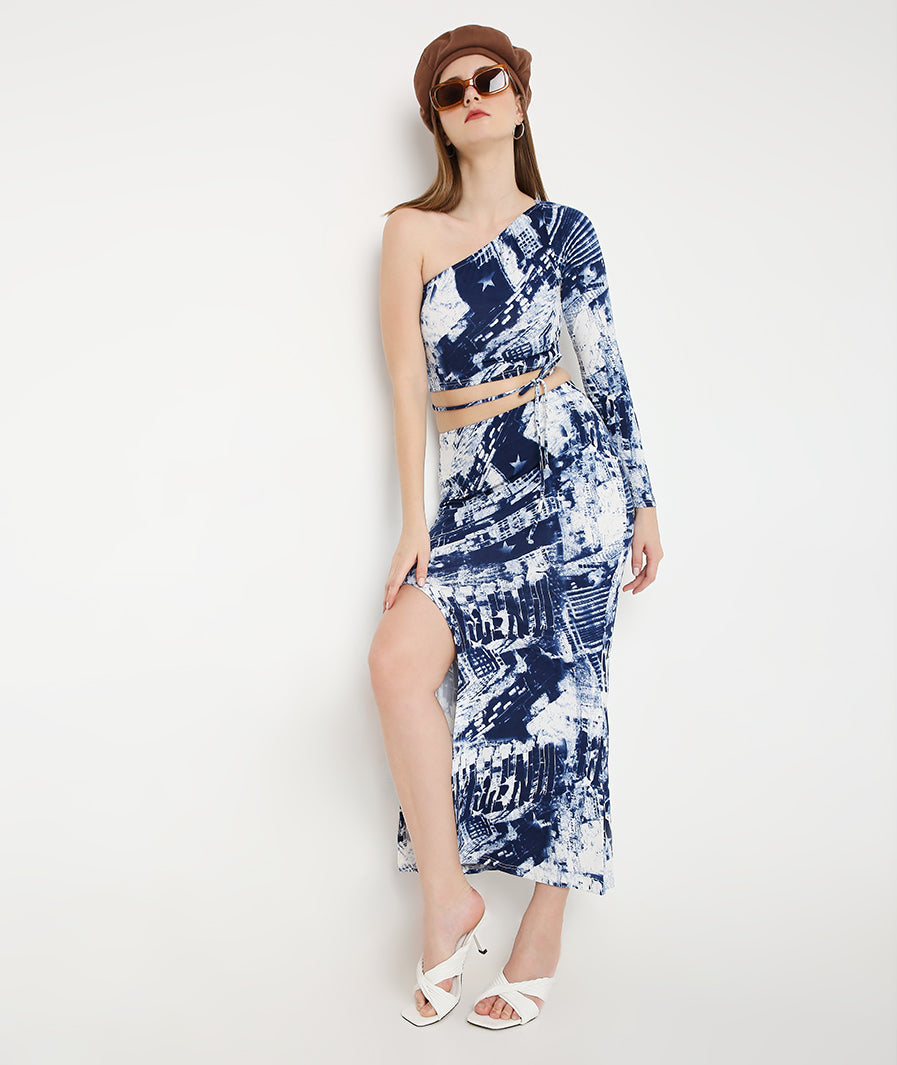 Marcel & Mae blue tie-dye co-ord set. Asymmetric off-shoulder top and front cut skirt. Designer two-piece outfit. Luxury resort wear ensemble. Blue printed party set. Statement festival clothing. Contemporary women fashion. Premium summer two-piece. Chic vacation outfit. Stylish one-shoulder crop top. High slit skirt set. High-end fashion apparel. Trendy designer co-ord. Sophisticated resort wear. Graphic tie-dye look.